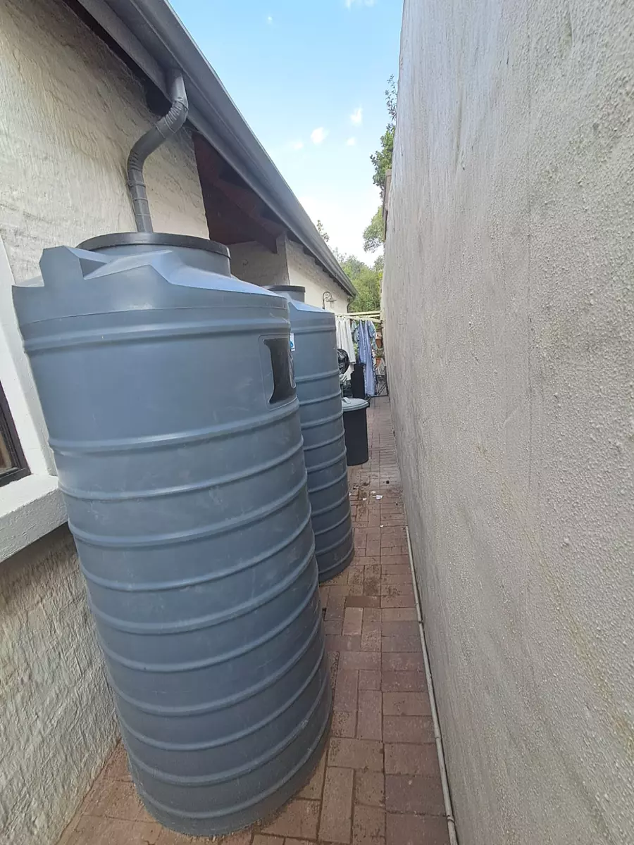 Two large grey water tanks in a narrow alley