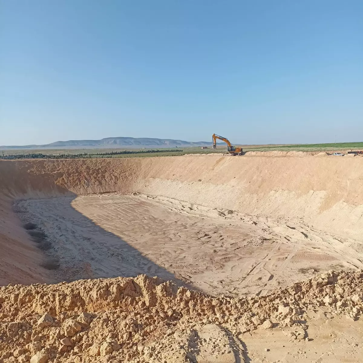 Excavation pit with an excavator in an arid landscape