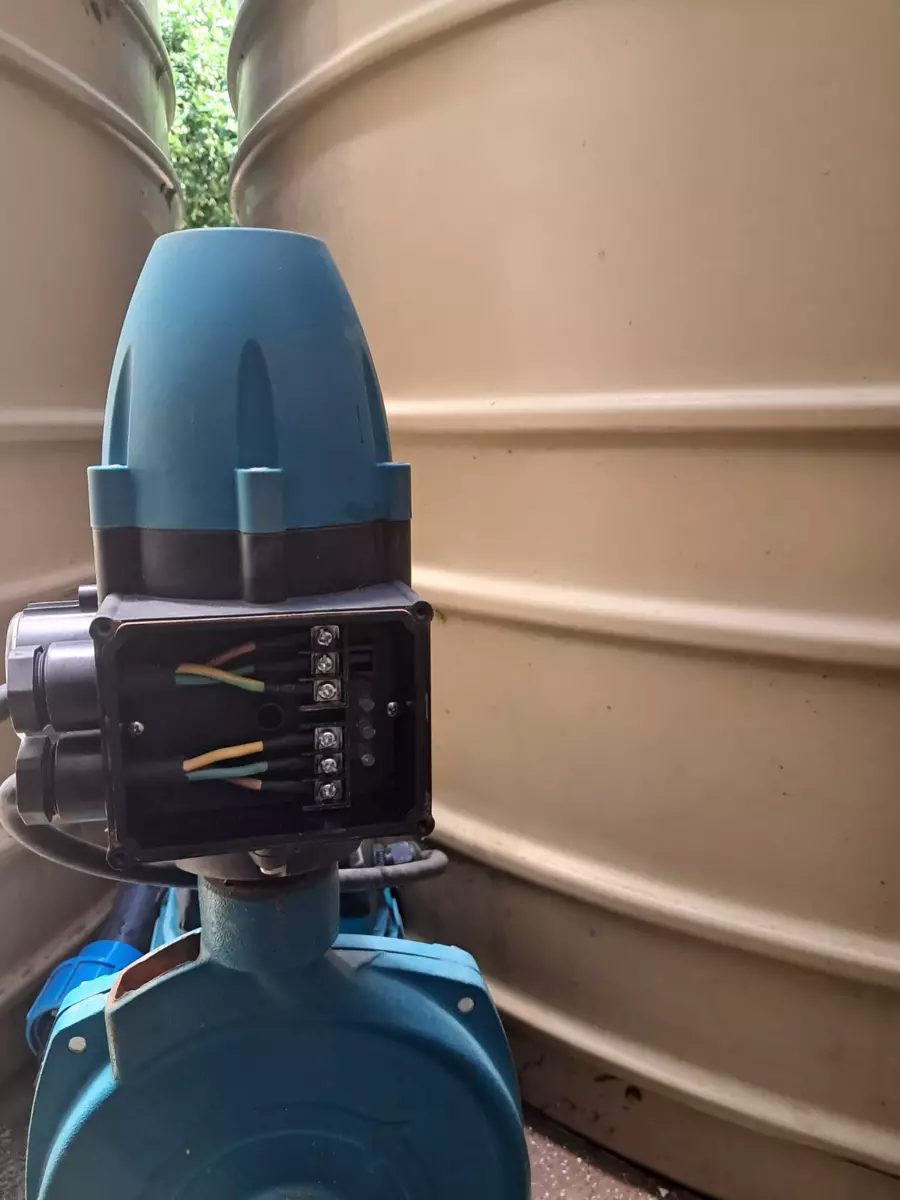 Blue water pump control unit in front of water storage tanks