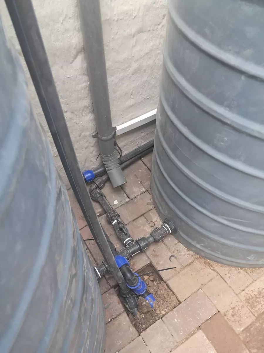 Two grey water tanks connected by plumbing pipes
