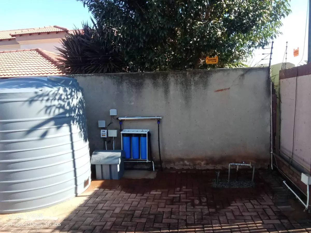 Water storage tank and filtration system installed against a wall