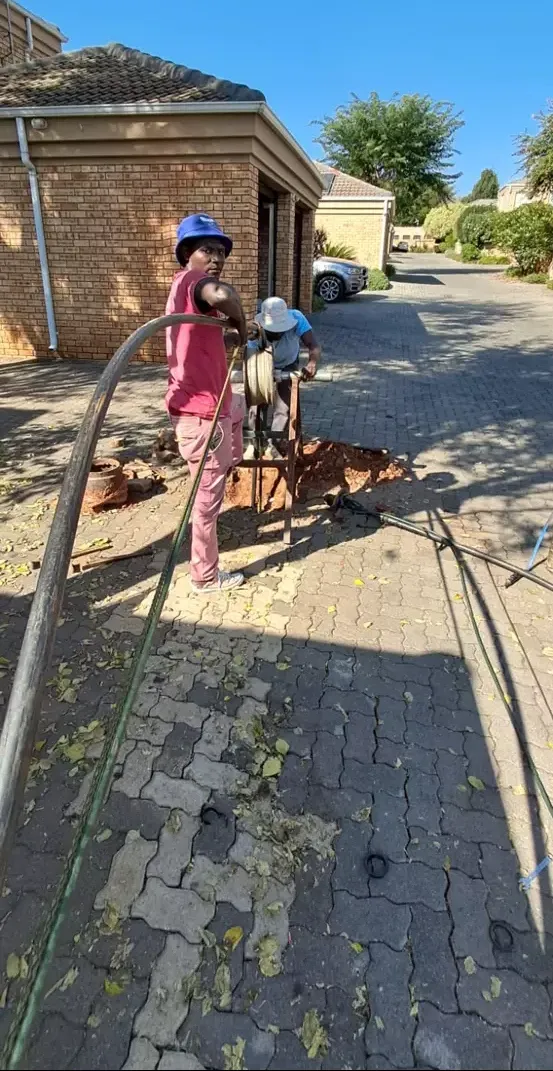 Workers installing cabling on a paved driveway