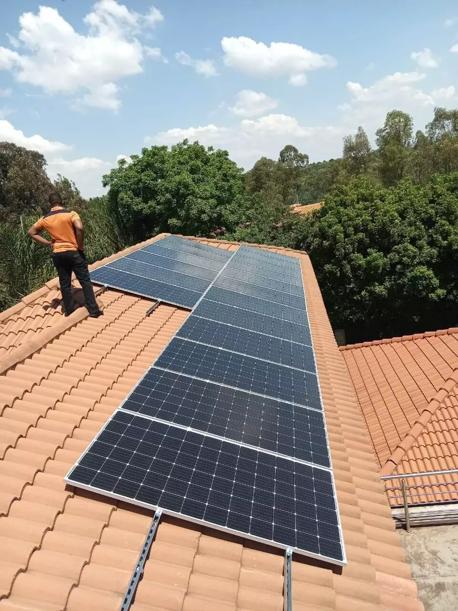 Solar panel installation on a terracotta tile roof with a technician