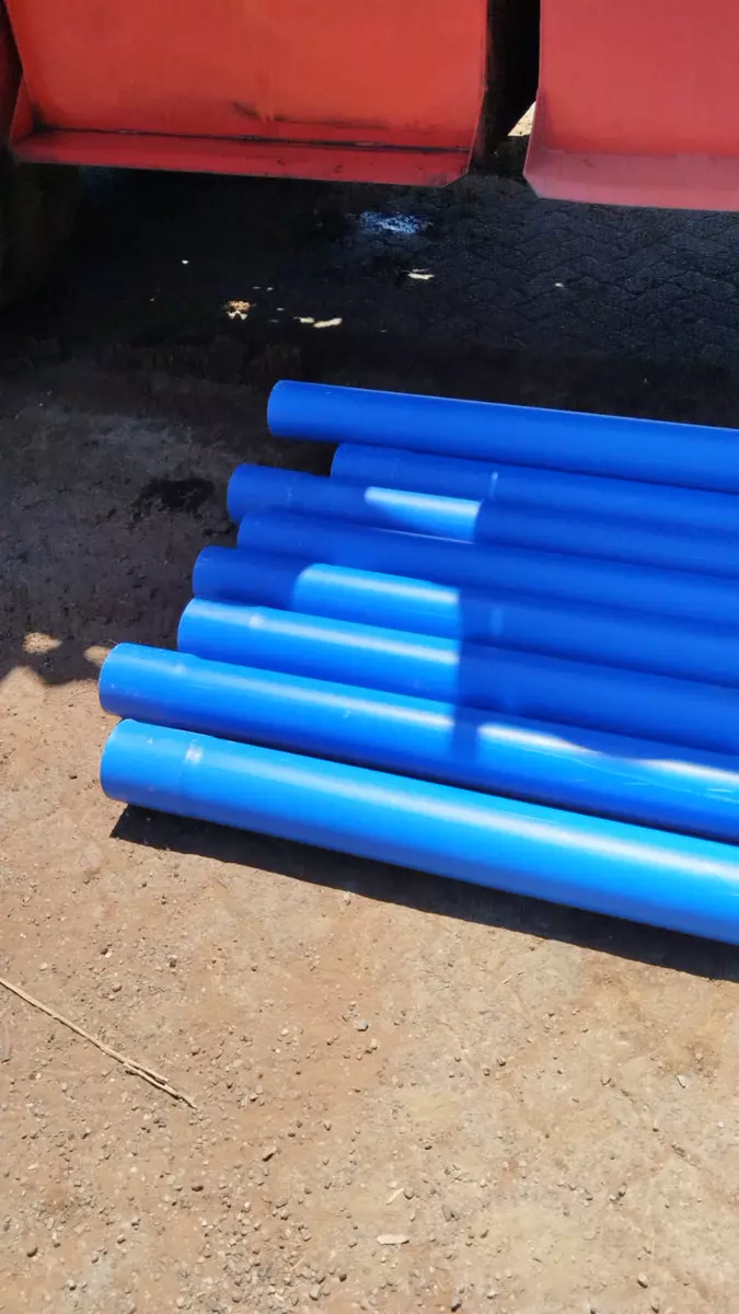 Stack of blue plastic pipes on dirt ground